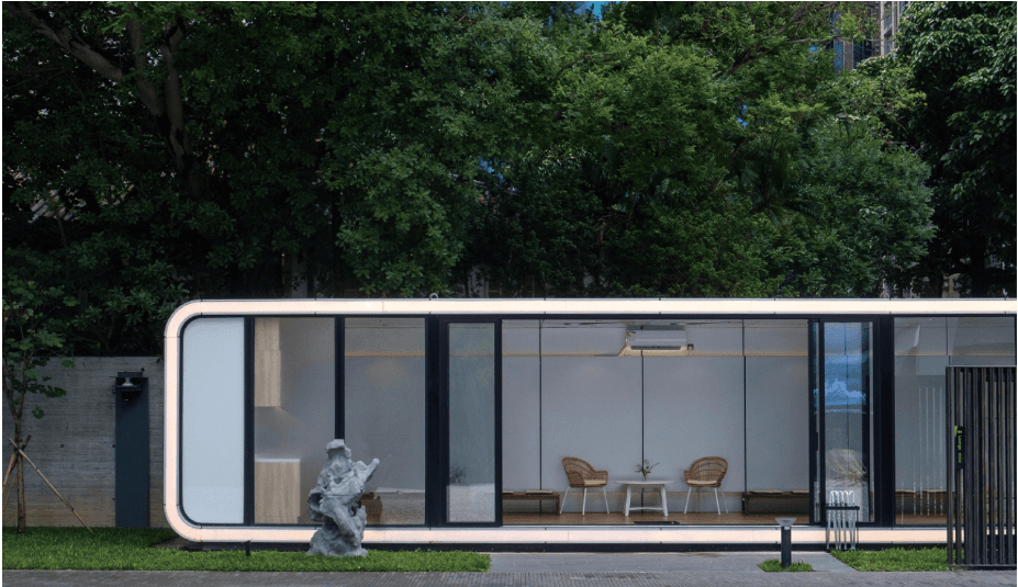 Rounded white Apple Cabin with a glass front in a park setting.