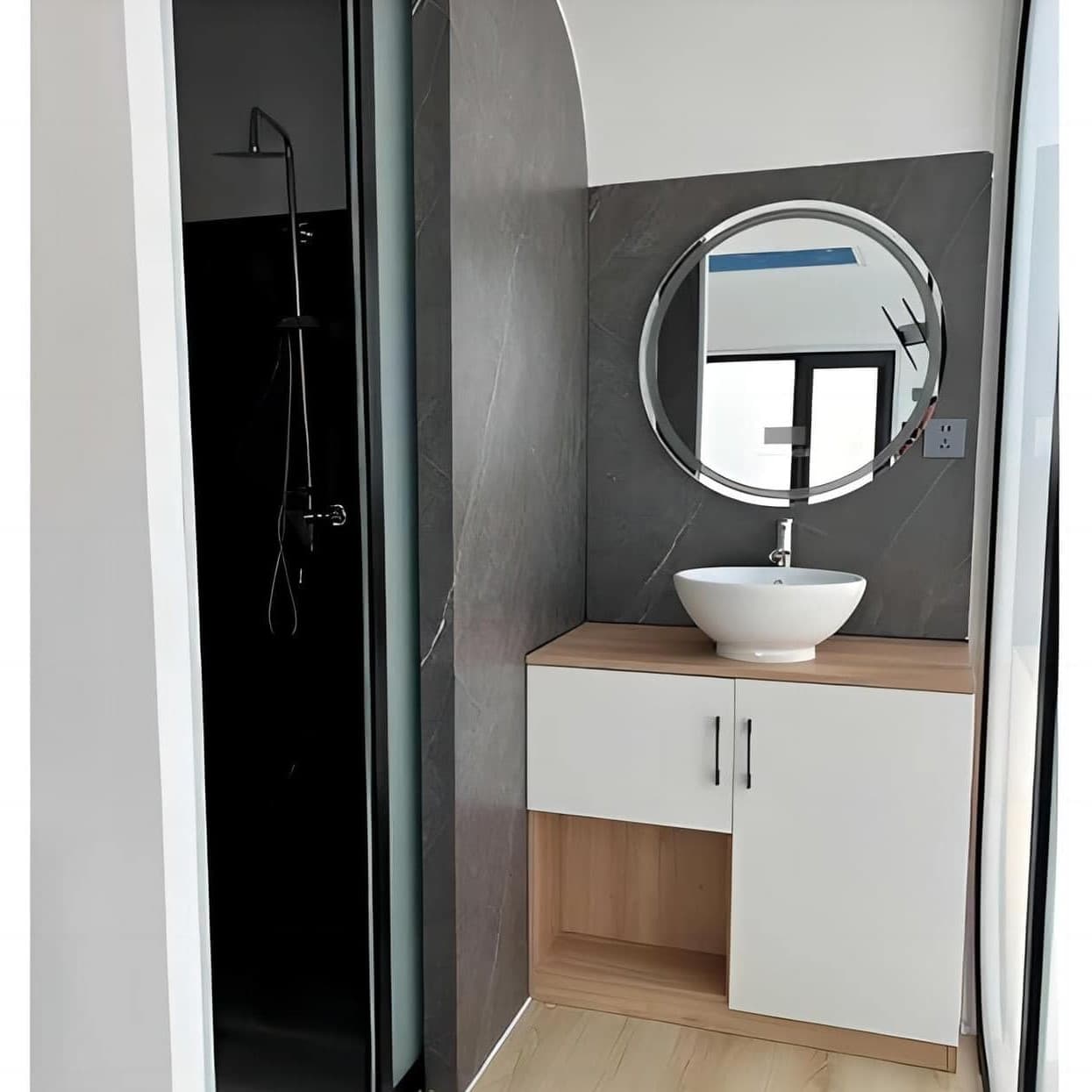 Apple Cabin bathroom with a round mirror, vessel sink, and walk-in shower.