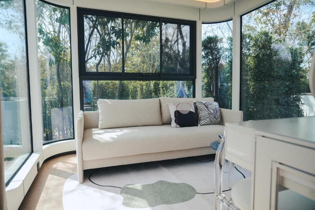 Apple Cabin lounge with a white sofa and curved floor-to-ceiling glass.