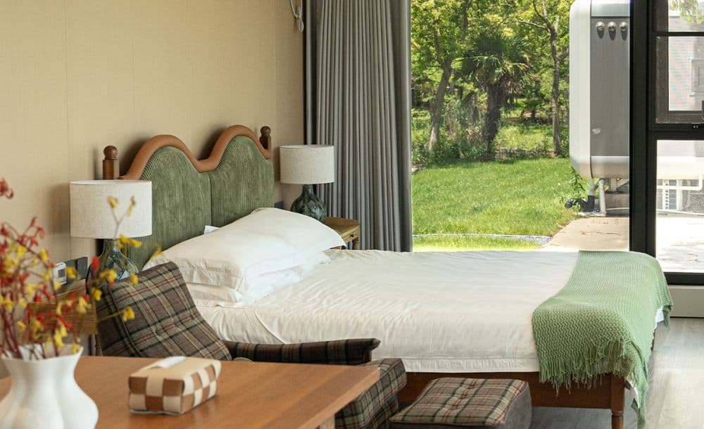 Apple Cabin bedroom with an upholstered headboard and a garden view.