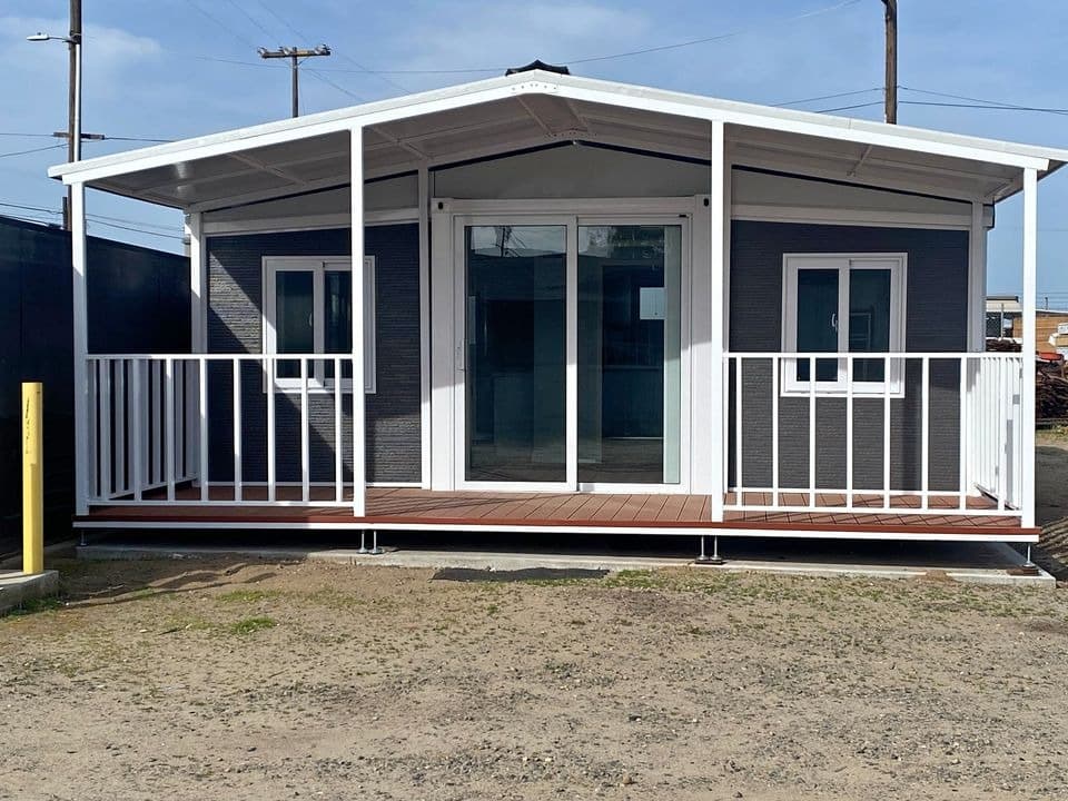 Gray 20x20 expandable home with a white covered porch, front view.