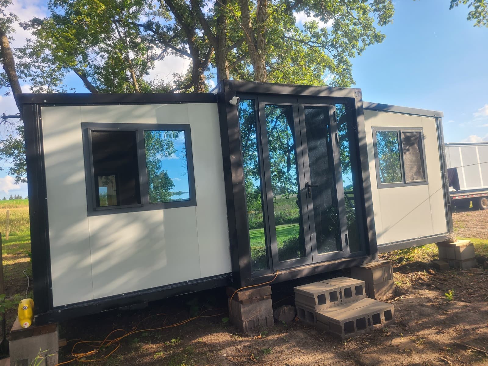 Expandable home with glass entry doors set on a wooded lot.