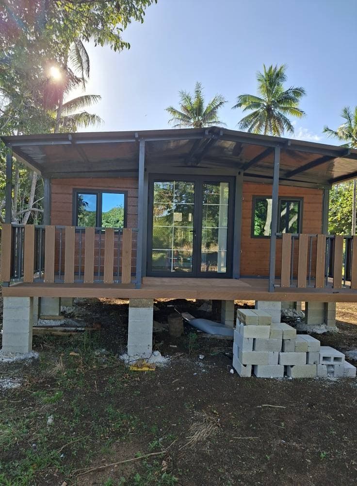 Side view of a delivered brown expandable home on a foundation.