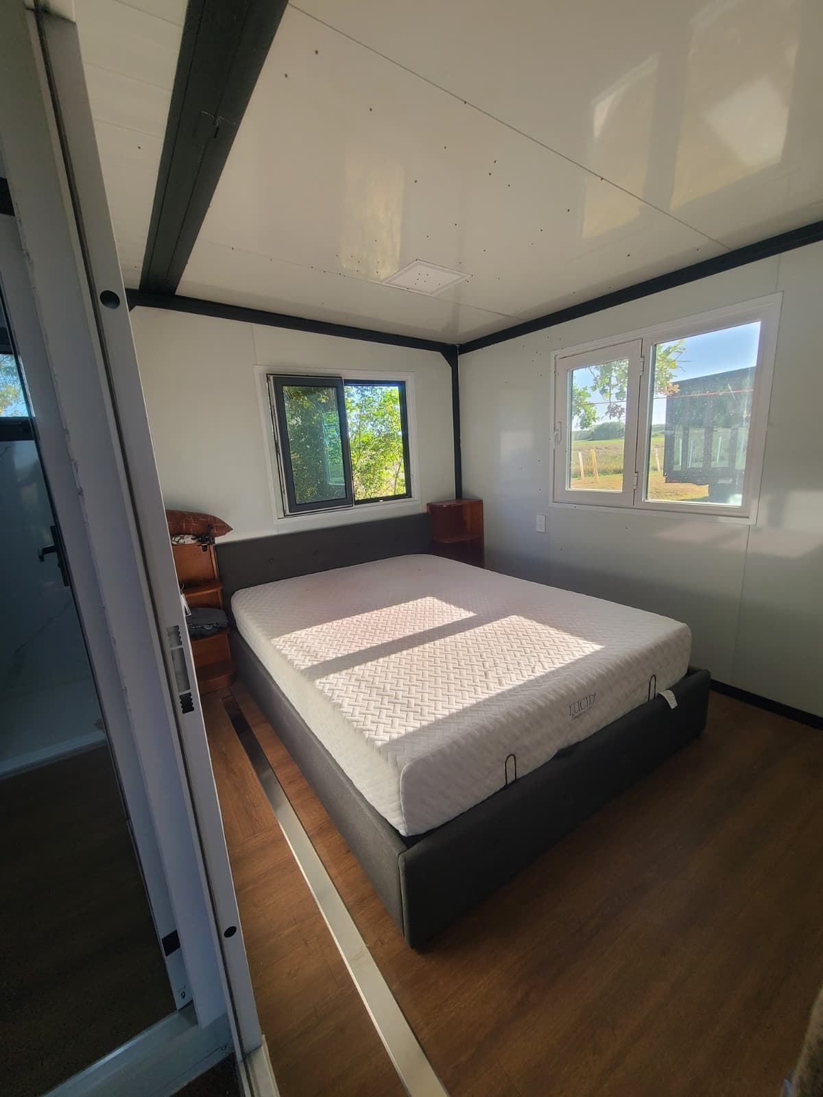 Expandable home bedroom with a queen bed and large windows.