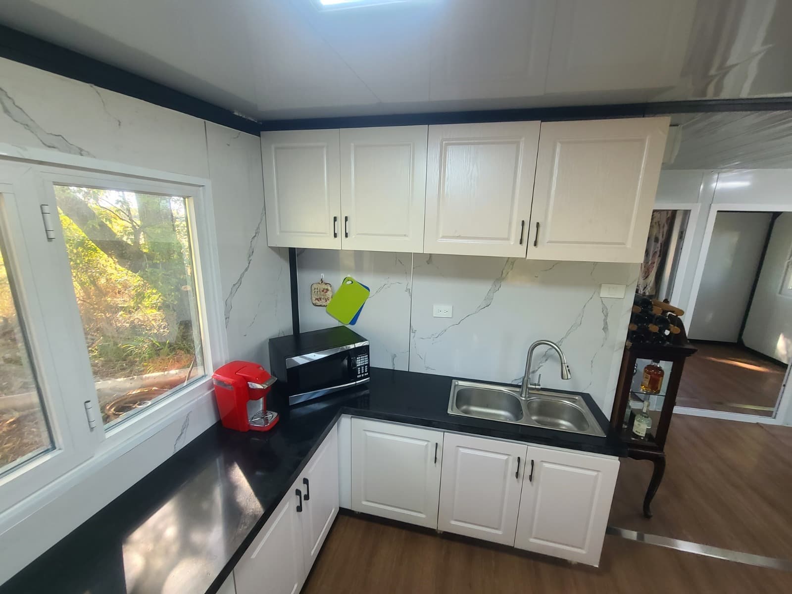 Expandable home kitchen with white cabinets and marble backsplash.