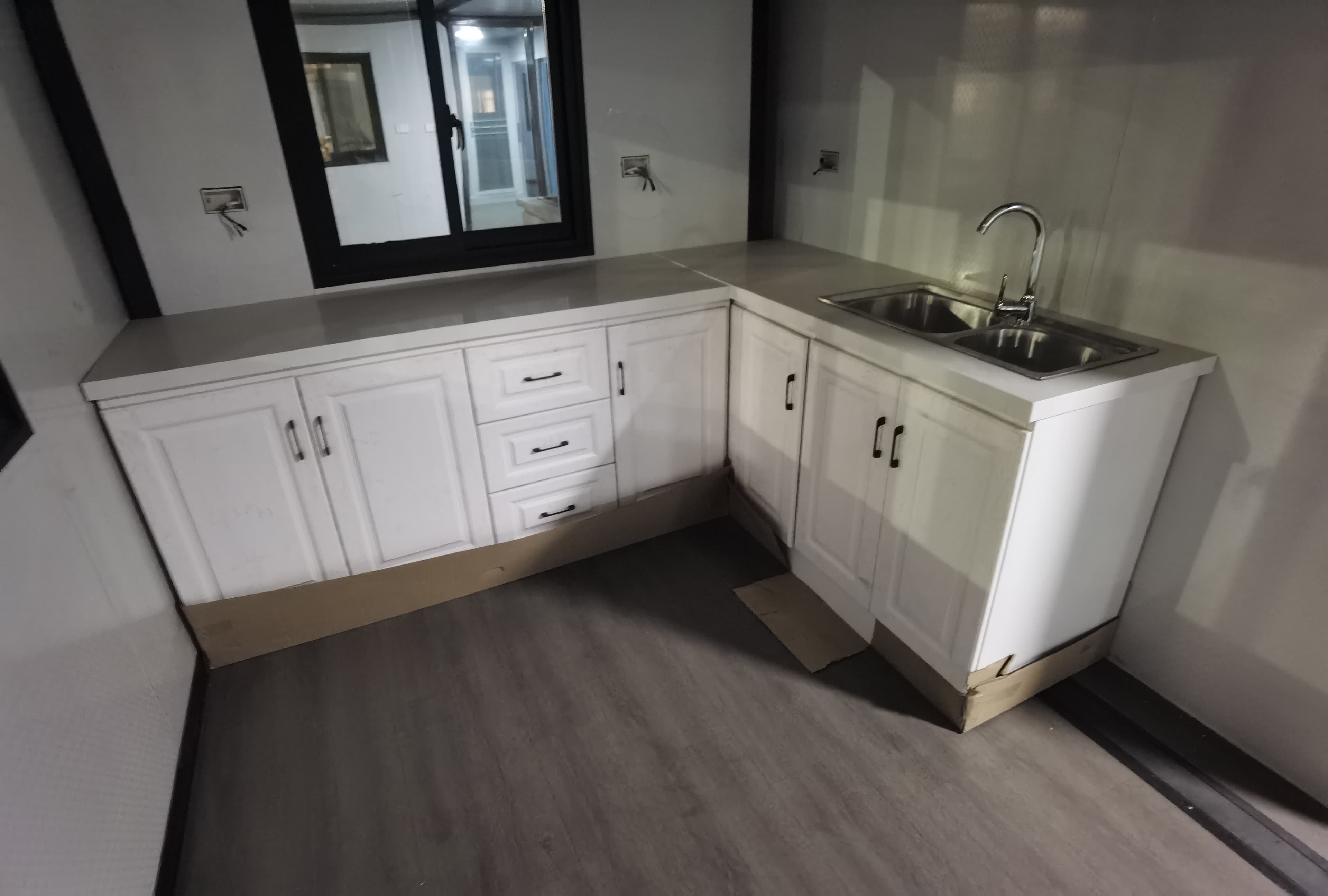 Expandable home kitchen with a double sink and white cabinetry.