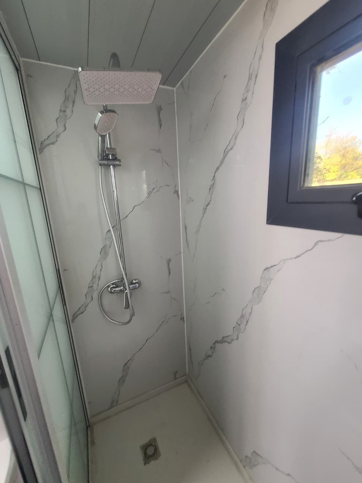 Walk-in shower with a rainfall head and marble walls.