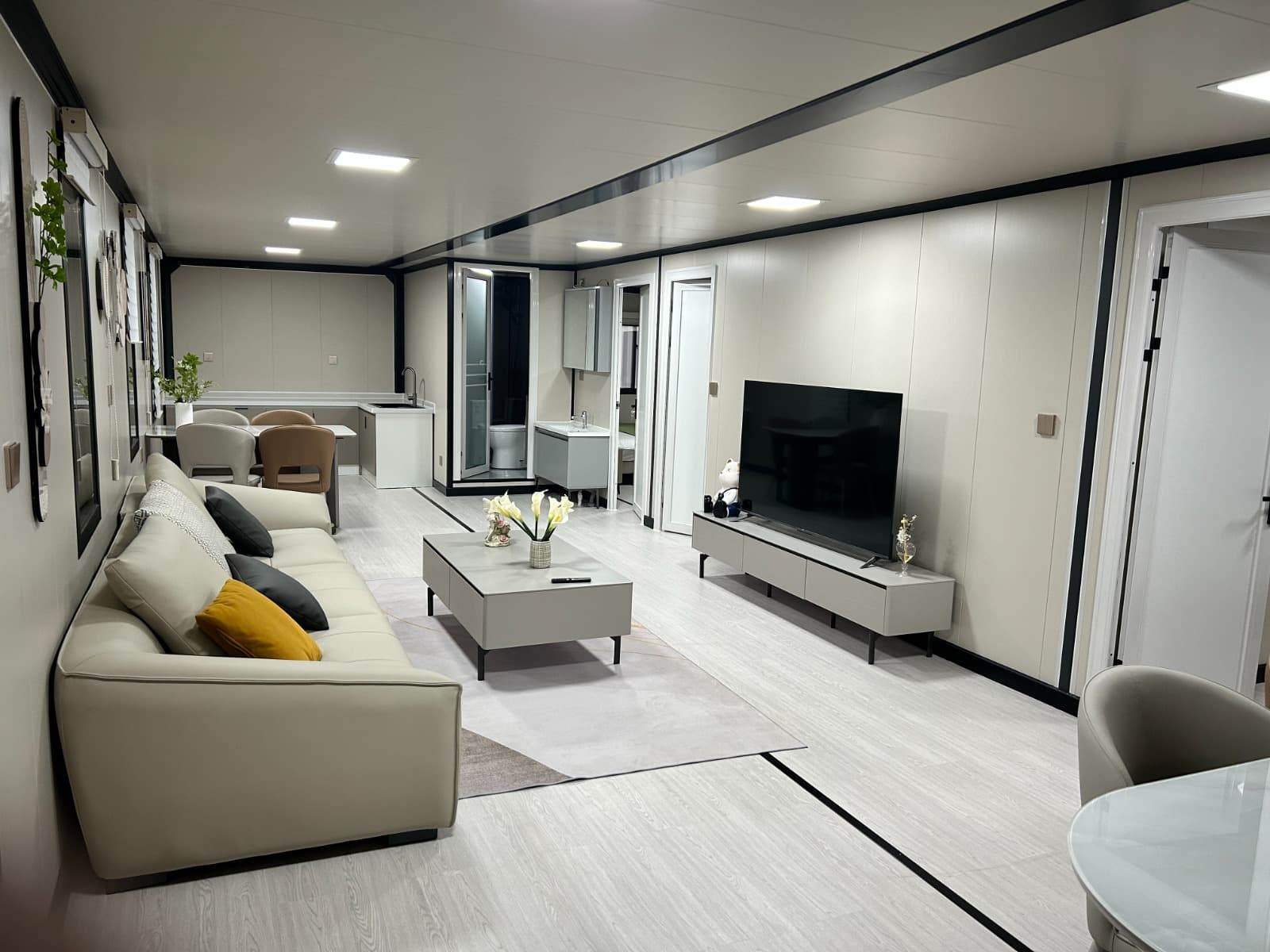 Furnished expandable living area with sofa, TV, and open kitchen.