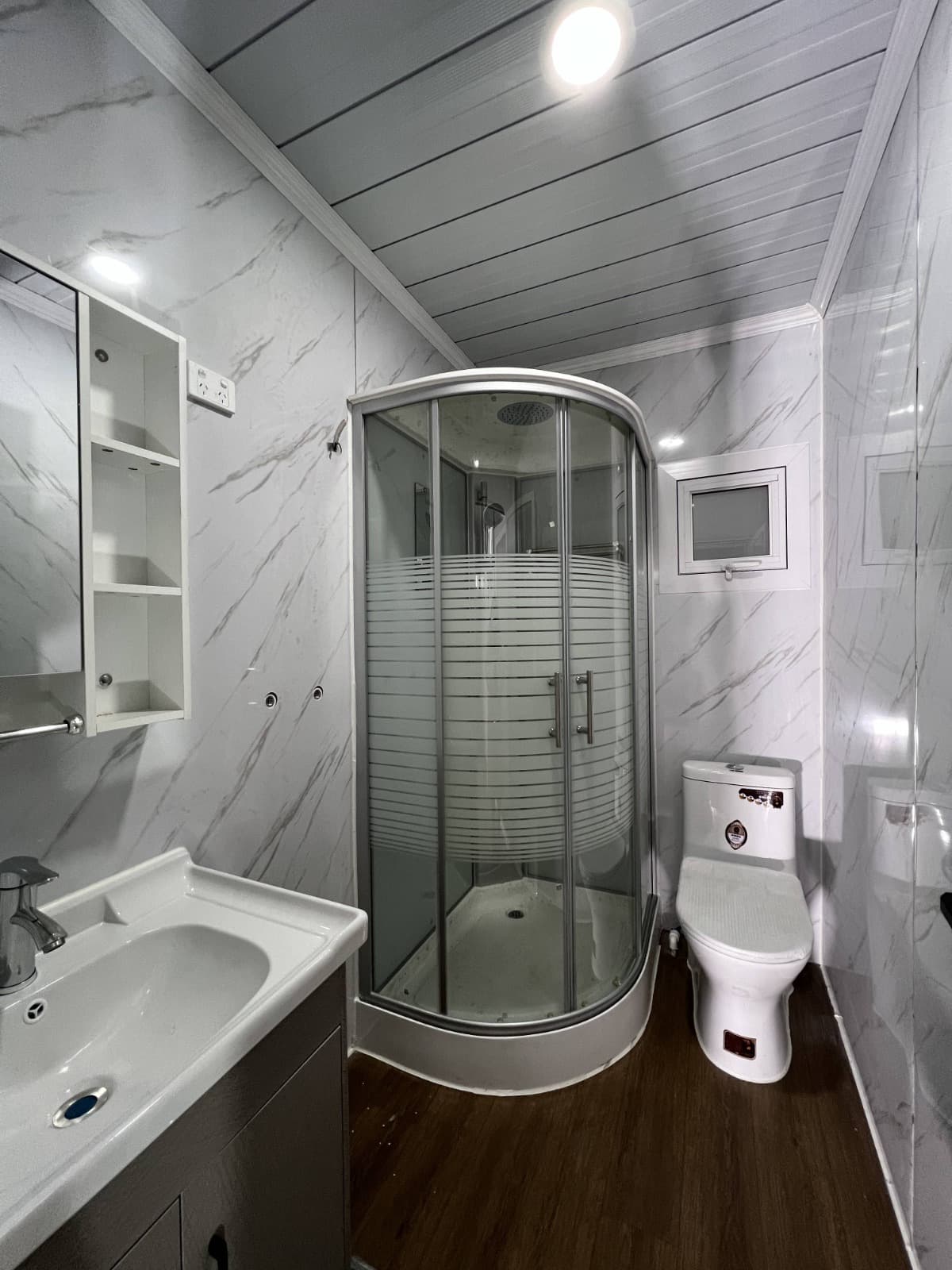 Expandable home bathroom with a curved glass shower and vanity.