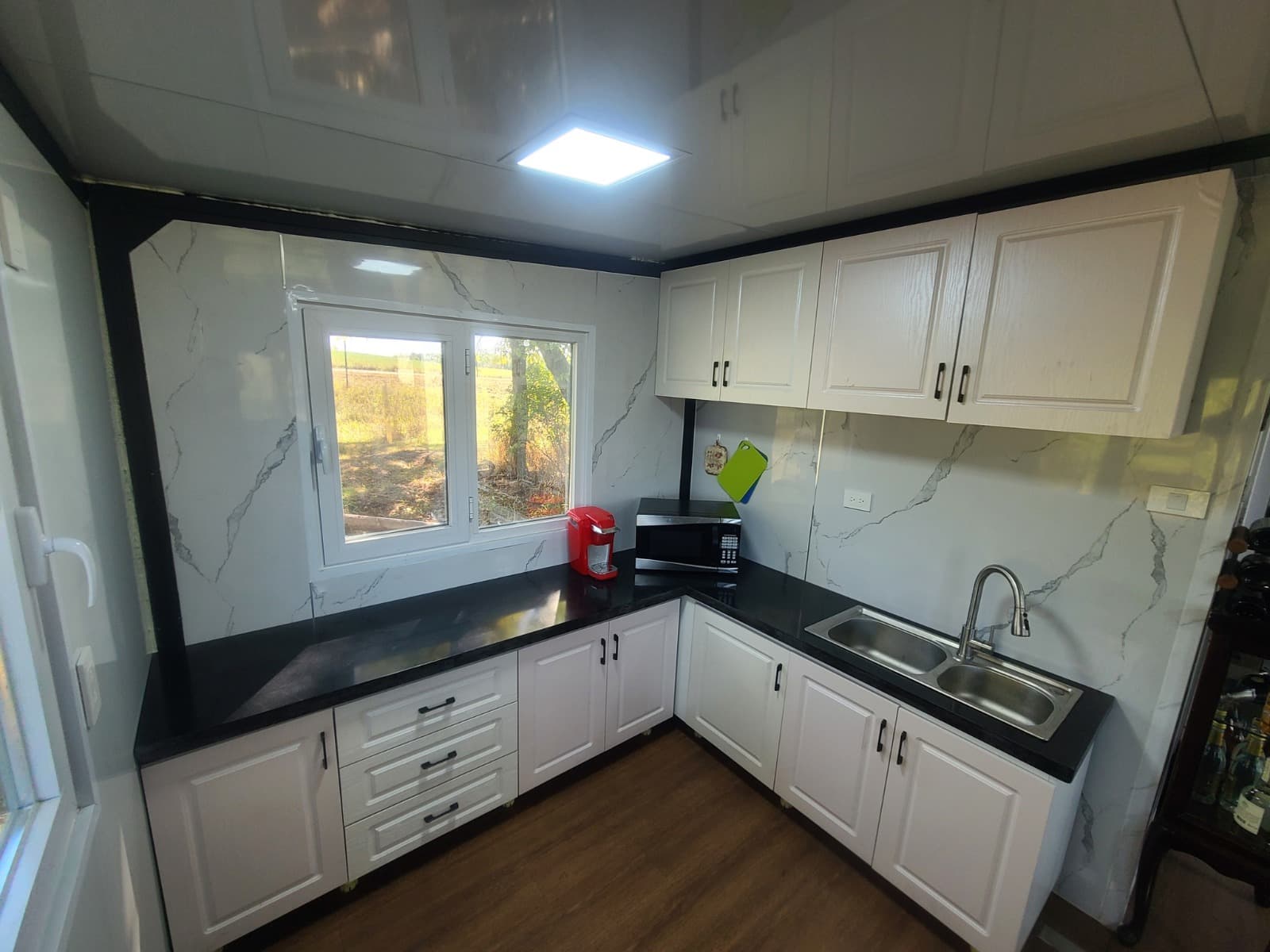 Expandable home kitchen with white cabinets and a black countertop.