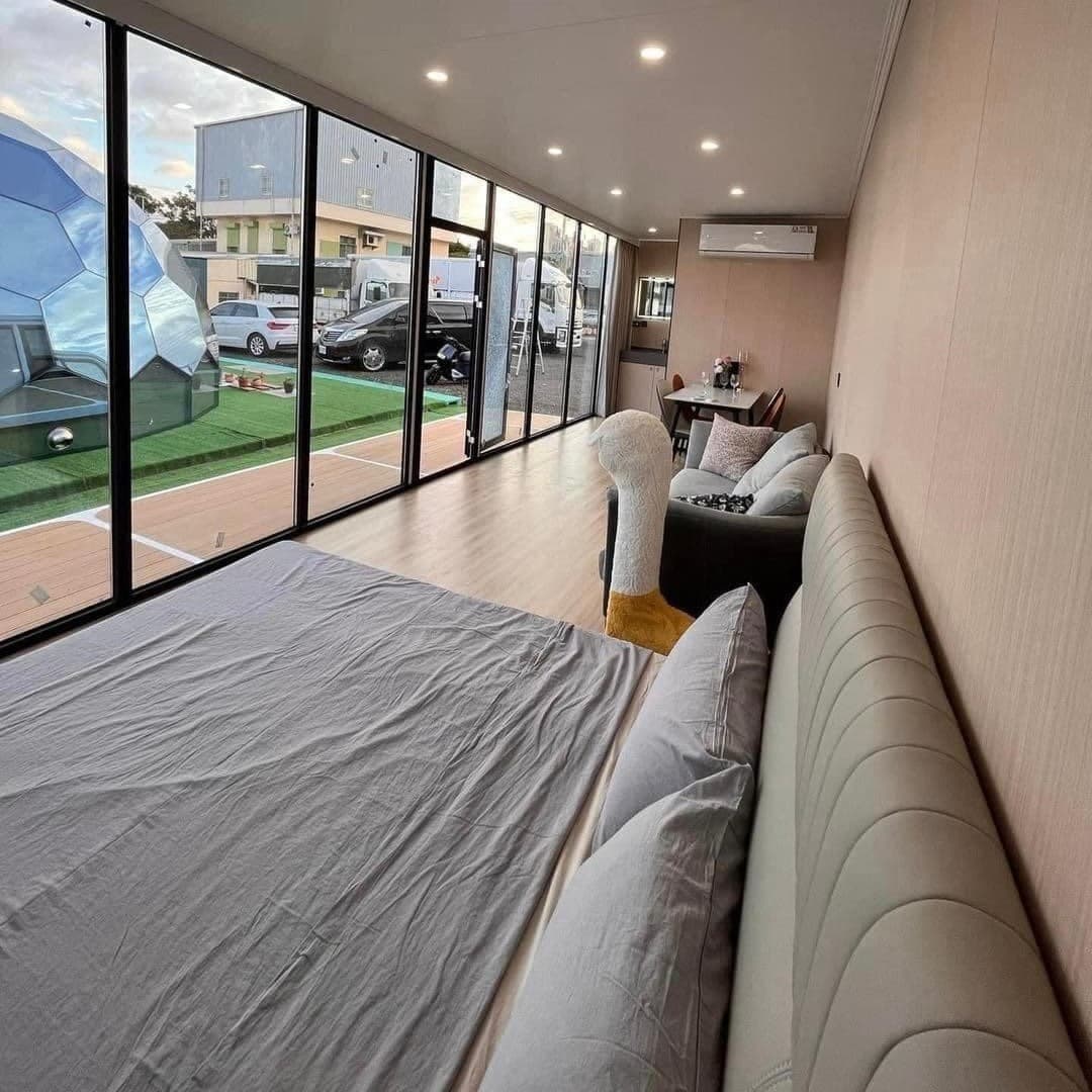 Space Capsule interior with a bed, sofa, and floor-to-ceiling glass.