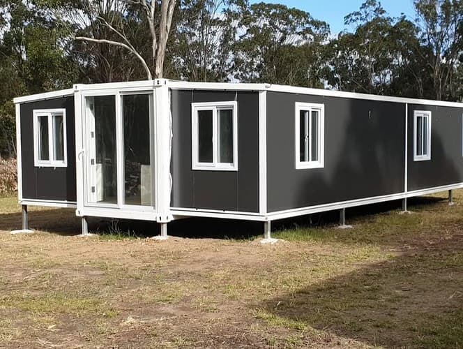 Gray and white 20x40 expandable home in an open field.